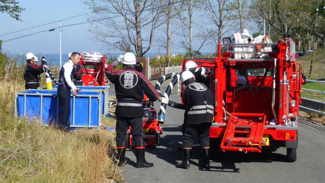 淡路市消防団のメンバーと一緒に準備を行う、（株）北淡建設・北淡路生コン工場 常務取締役工場長の芦野晴貴氏（左から2人目）。