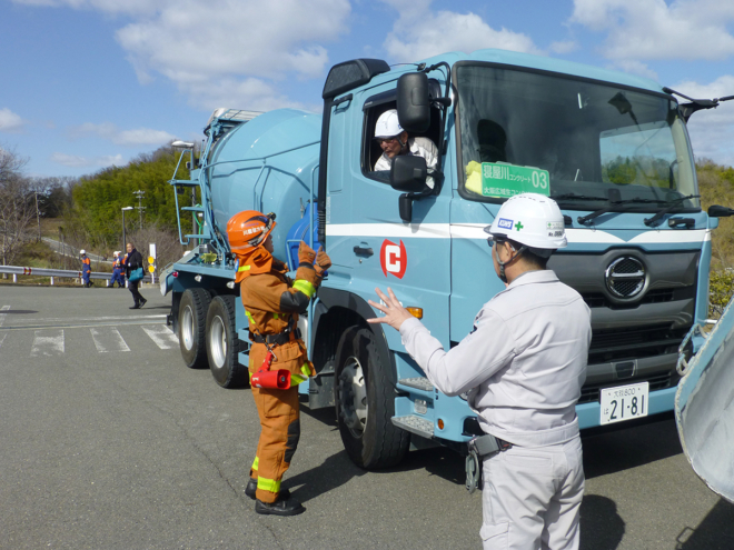 枚方東消防署の署員と段取りの打ち合わせを行う、KLWS加盟事業者の生コン車ドライバー。