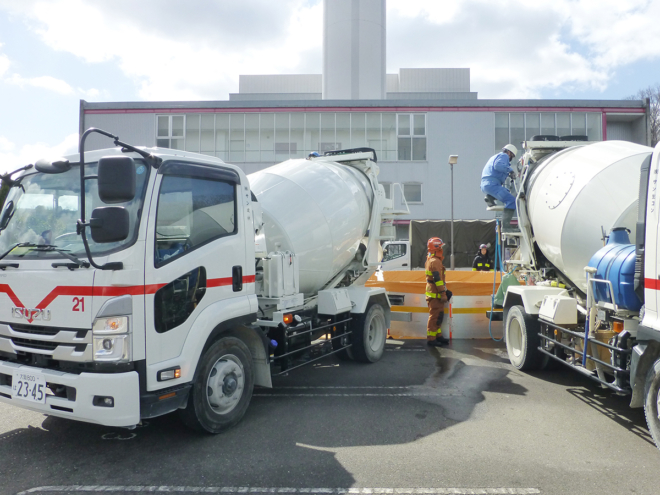 20tの水槽に注水する、（株）サン生コンと寝屋川コンクリート（株）の生コン車。